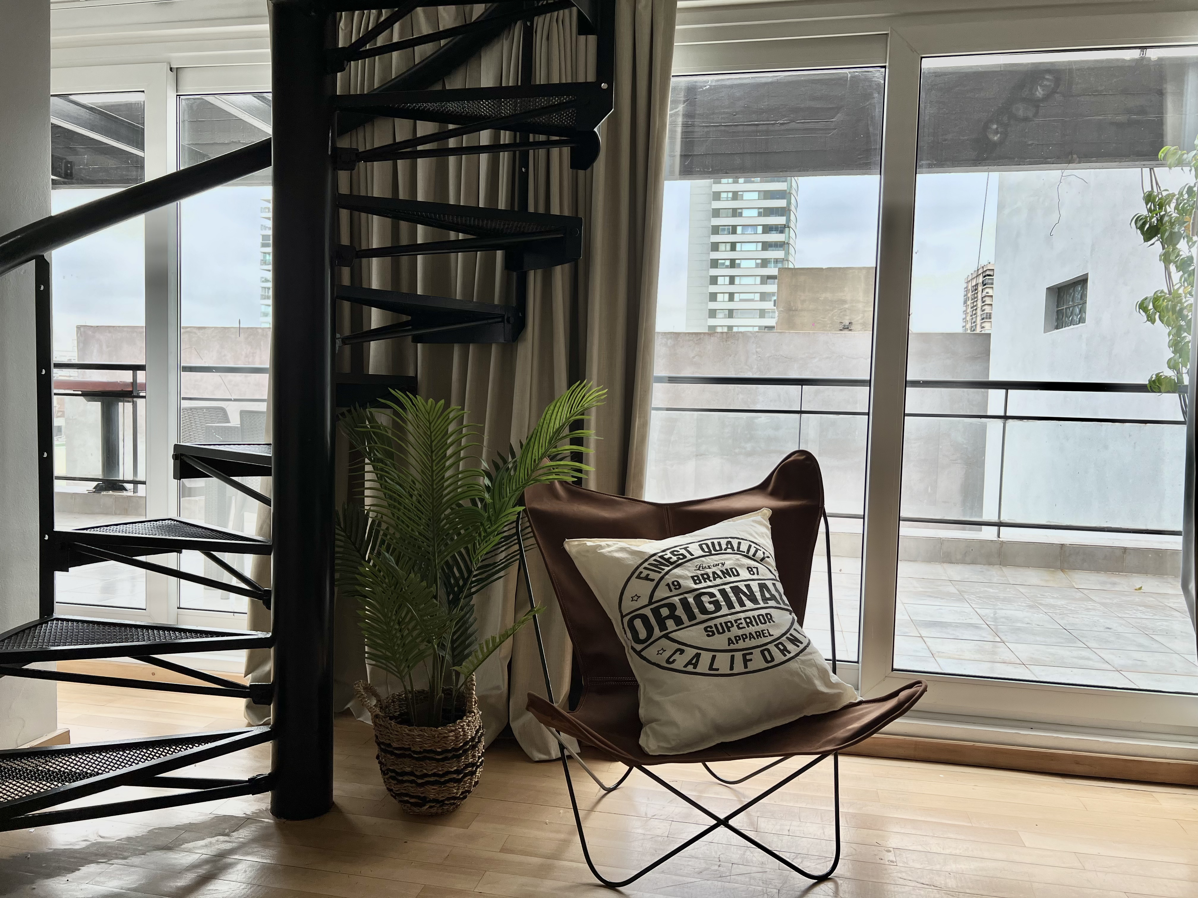 Escalera caracol con sillón butterfly y terraza